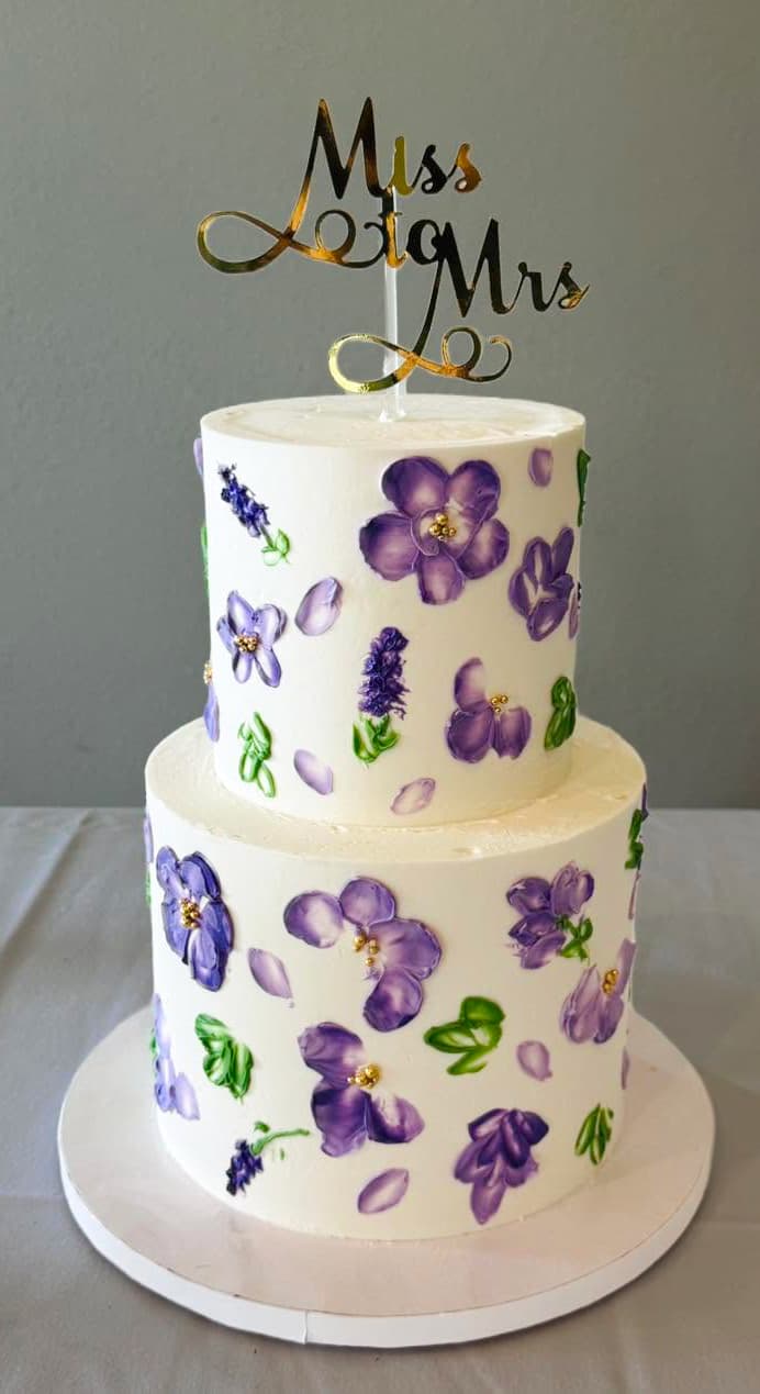 Two-tier celebration cake decorated with hand-painted purple flowers