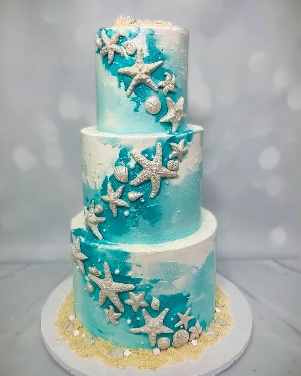 Three-tier ocean-inspired wedding cake with starfish, seashells and turquoise details