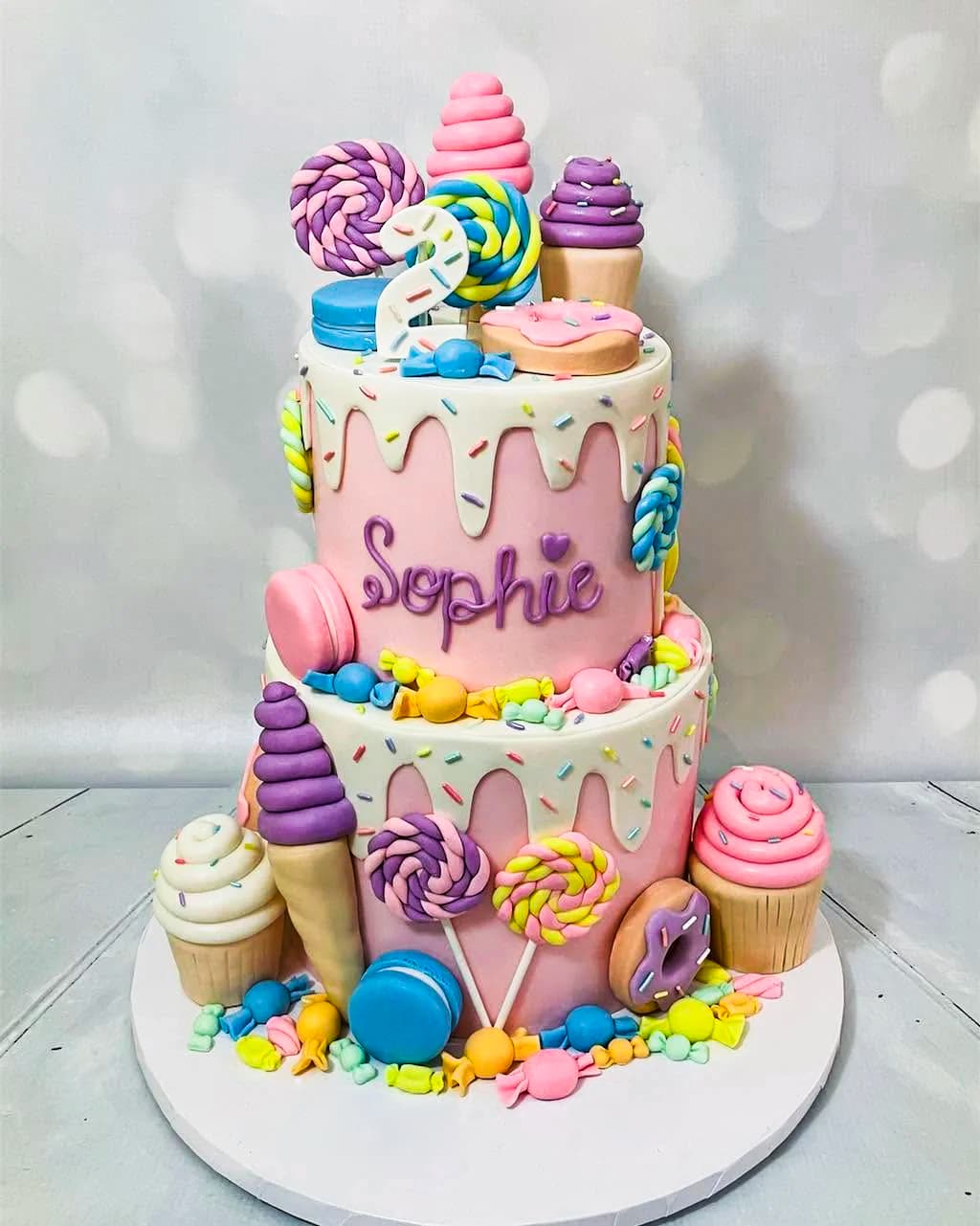Pastel custom birthday cake with lollipops, macarons and cupcakes by Sweet Cakes by Kristen