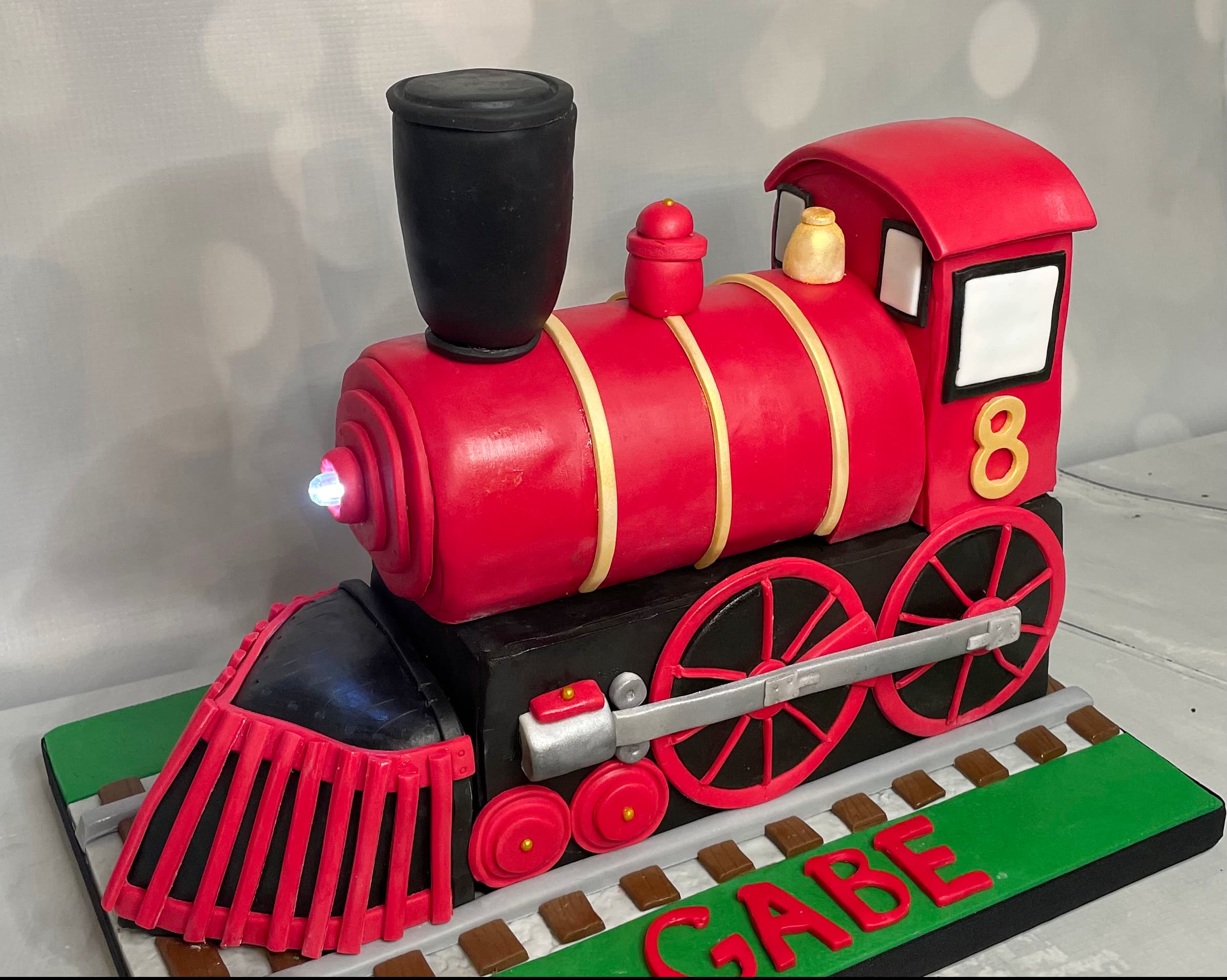 Sculpted red train birthday cake with detailed locomotive design by Sweet Cakes by Kristen