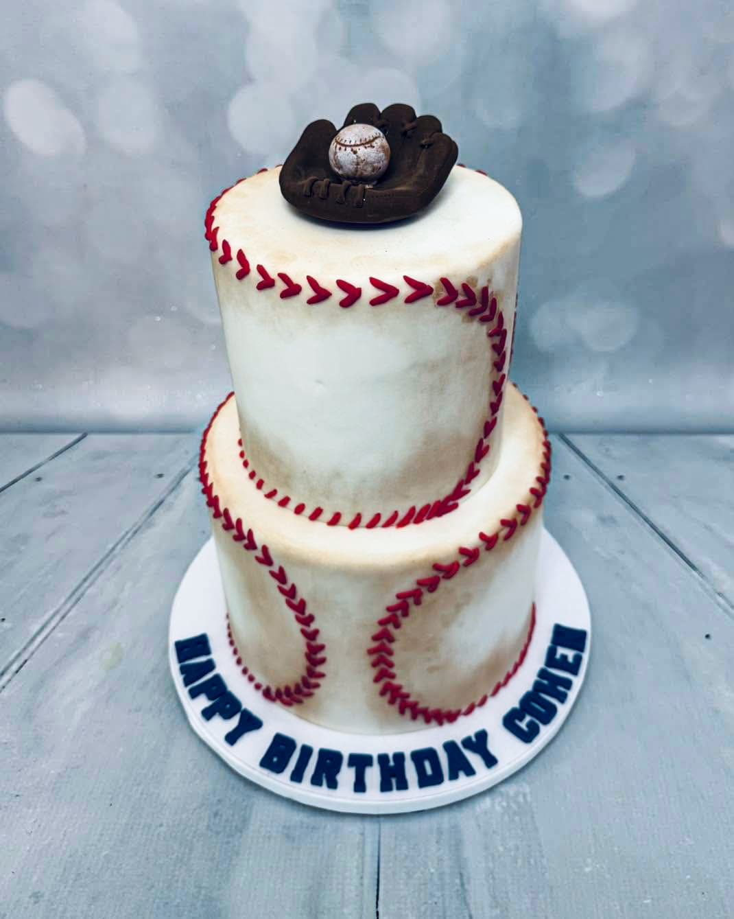 Baseball themed two-tier birthday cake with baseball stitching and glove topper by Sweet Cakes by Kristen