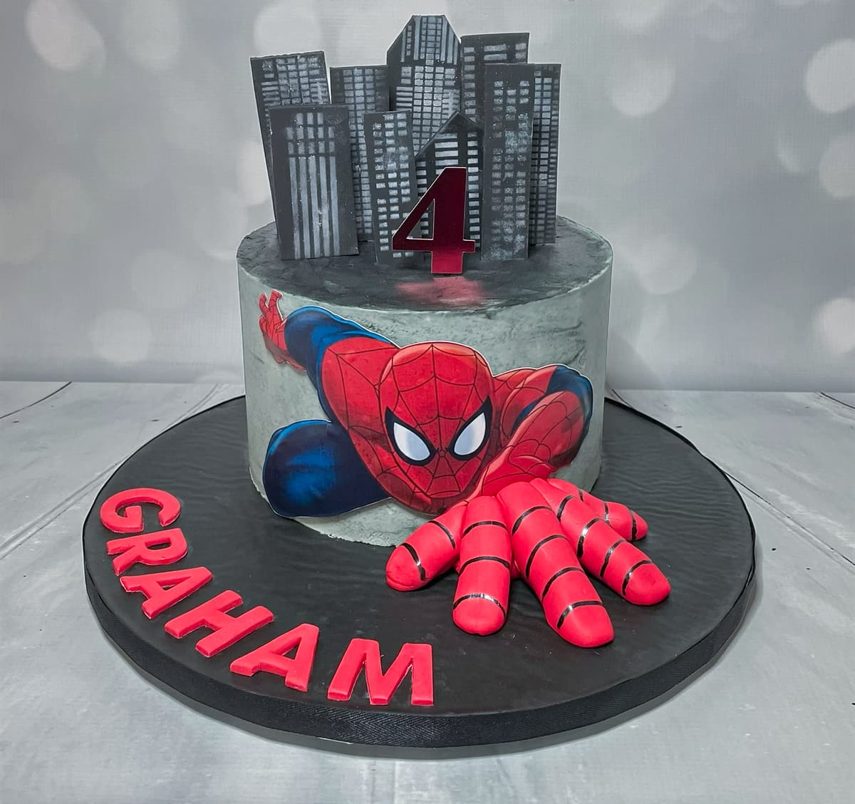 Spider-Man inspired birthday cake with city skyline and sculpted superhero details by Sweet Cakes by Kristen