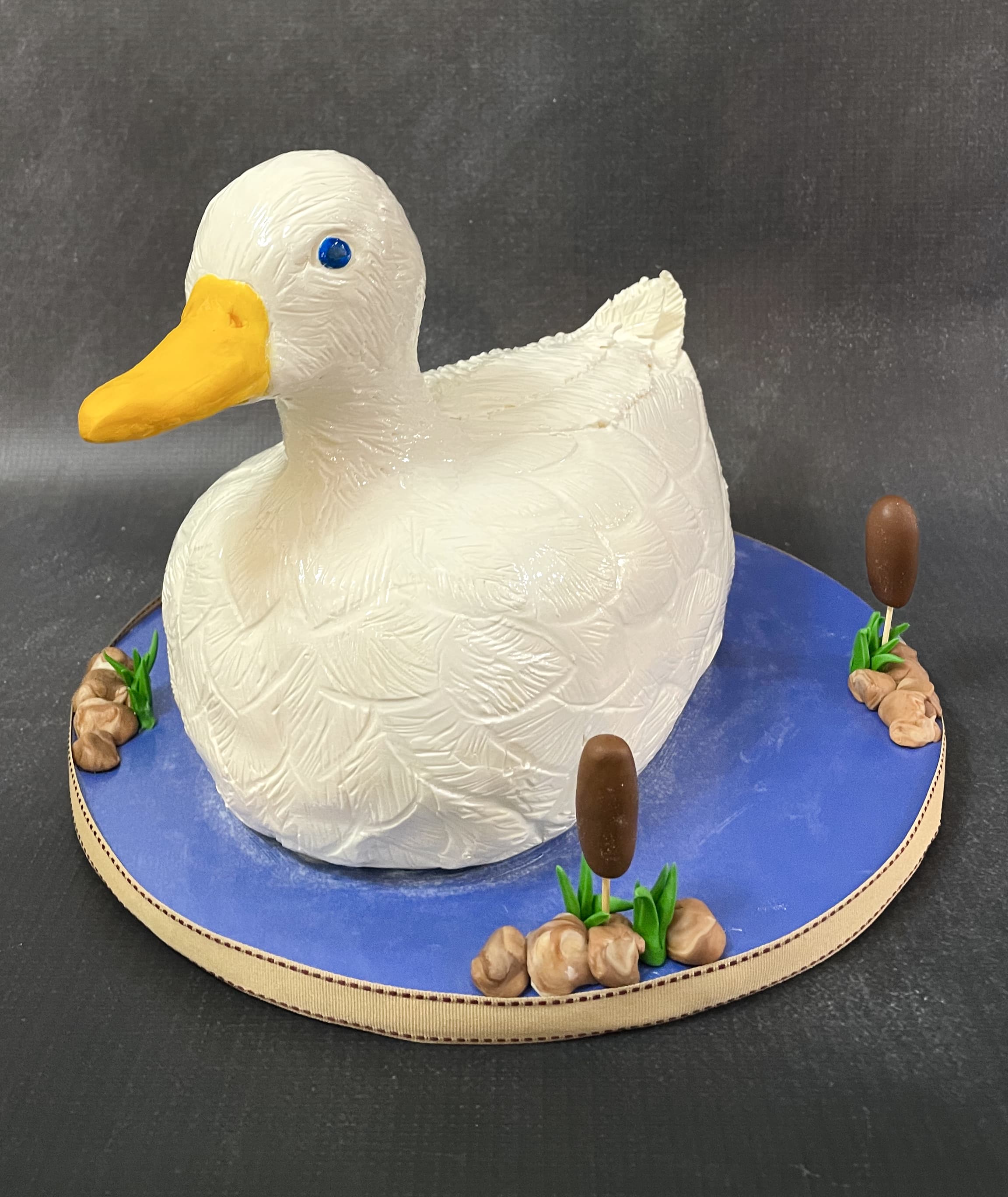 Realistic three-dimensional sculpted white duck cake with pond and cattail details by Sweet Cakes by Kristen