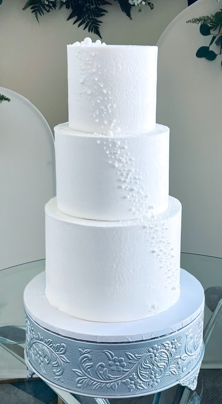 Elegant white wedding cake with detailed tiers by Sweet Cakes by Kristen