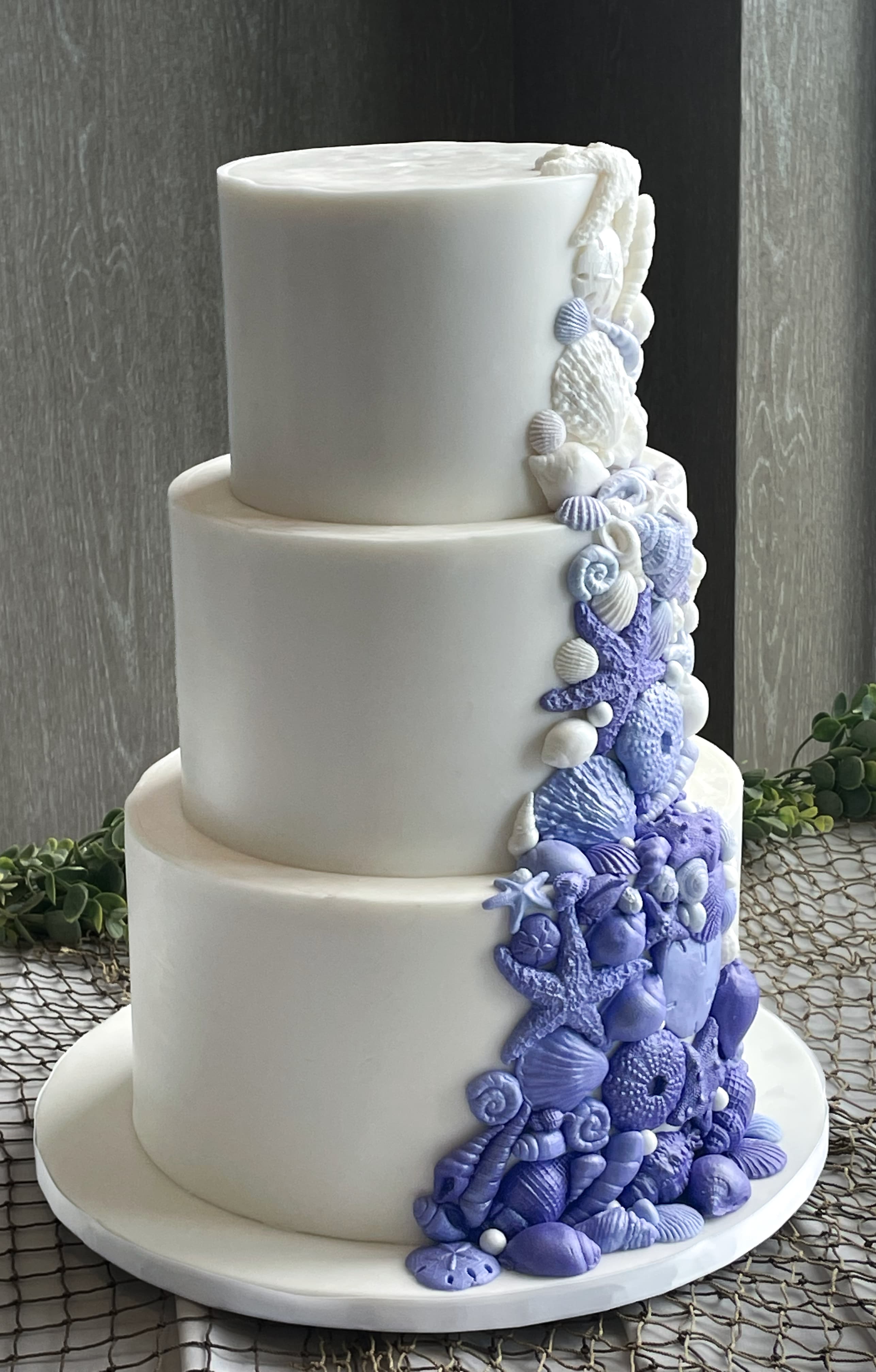 Modern three-tier white wedding cake with cascading lavender flowers by Sweet Cakes by Kristen