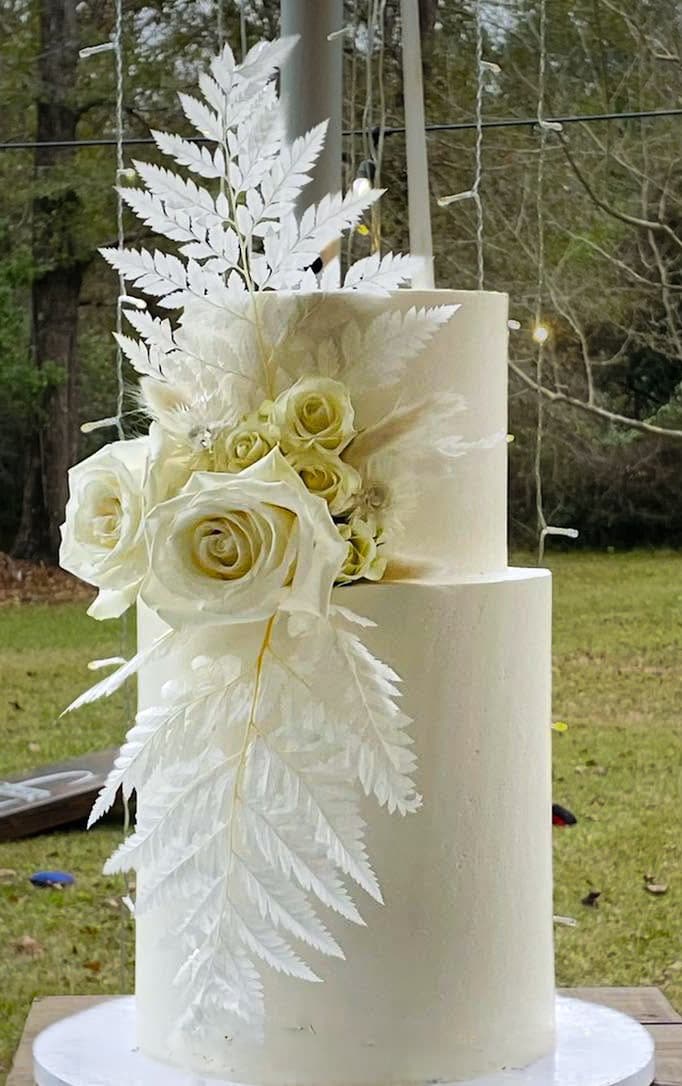 Elegant white wedding cake with cascading white flowers and decorative foliage by Sweet Cakes by Kristen