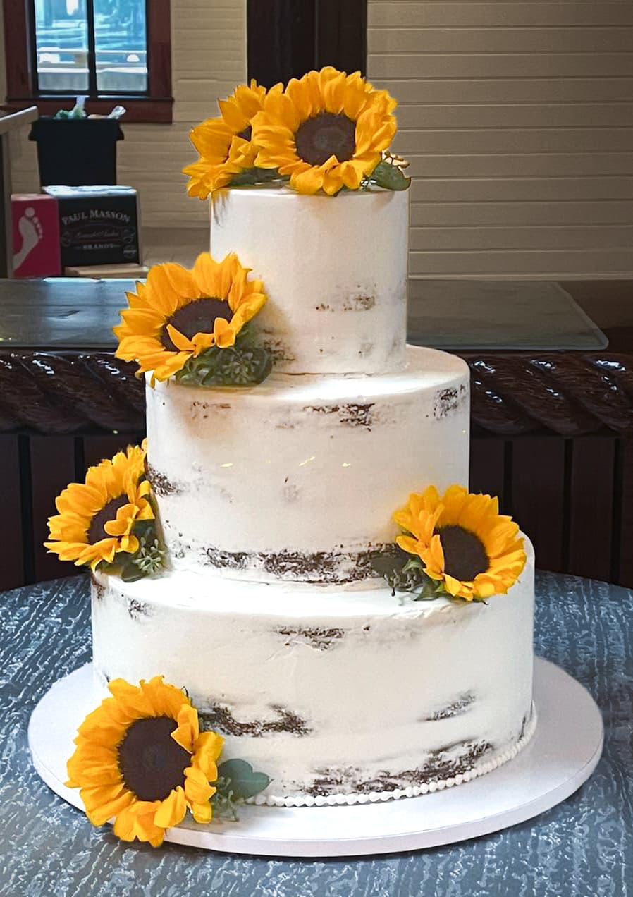 Rustic three-tier semi-naked wedding cake decorated with bright sunflowers by Sweet Cakes by Kristen